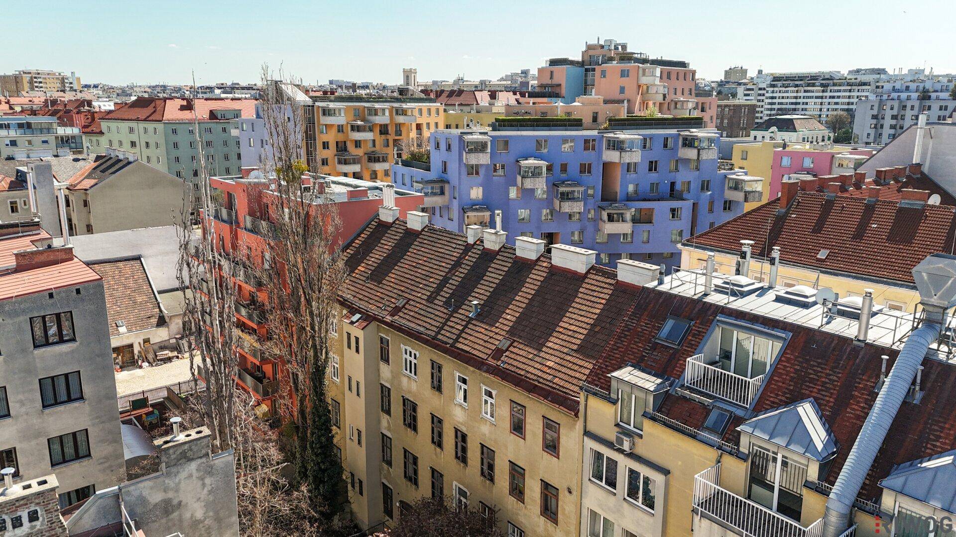 Luftaufnahme einer städtischen Straße mit parkenden Autos und angrenzenden Wohngebäuden.