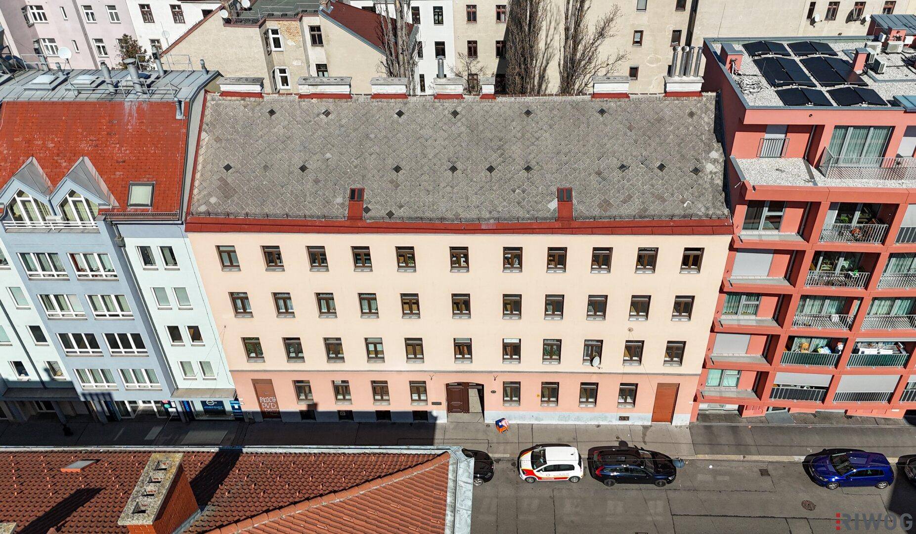 Stadtansicht mit einer Reihe von Gebäuden und einem modernen Wohnkomplex unter blauem Himmel.