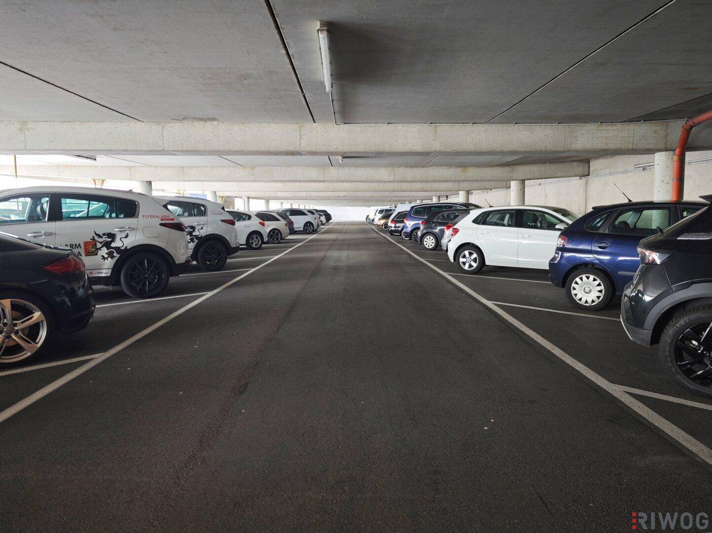 Tiefgarage mit zahlreichen Stellplätzen und Betonkonstruktion, gut beleuchtet.