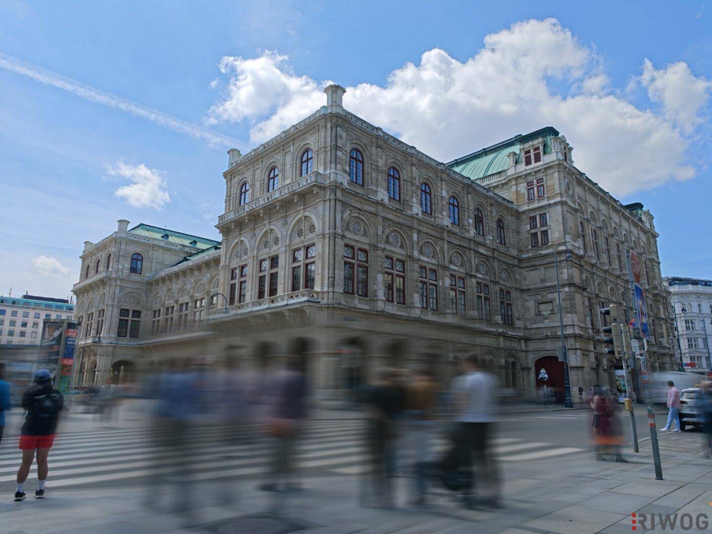 Historisches Operngebäude in Wien mit klassischer Architektur und belebter Straße davor.