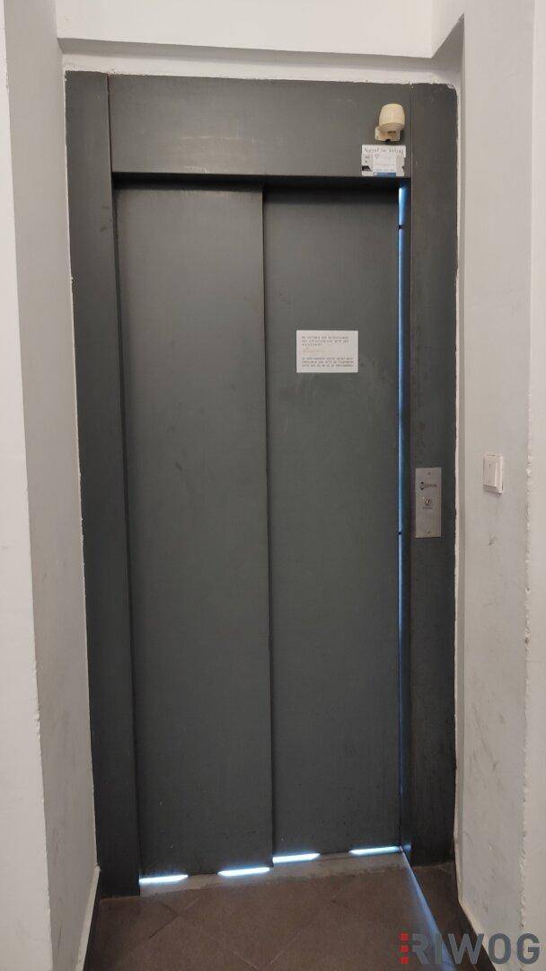 Dunkle Aufzugstür in einem Flur, bereit für die Nutzung durch Bewohner.