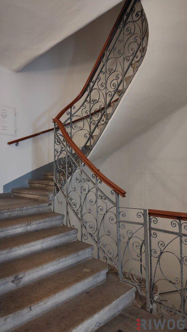 Historisches Treppenhaus mit schmiedeeisernem Geländer und Holzhandlauf.