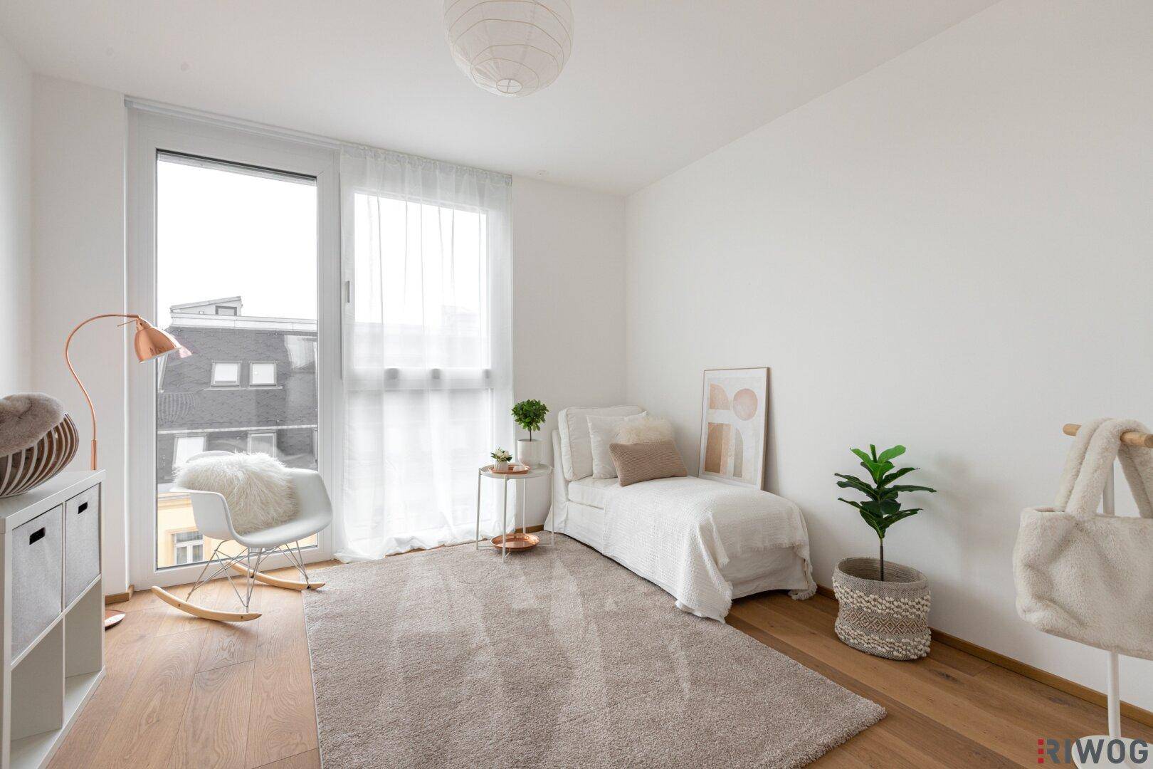 Gemütliches Zimmer mit Holzboden, Tagesliege und großem Fenster für viel Tageslicht.