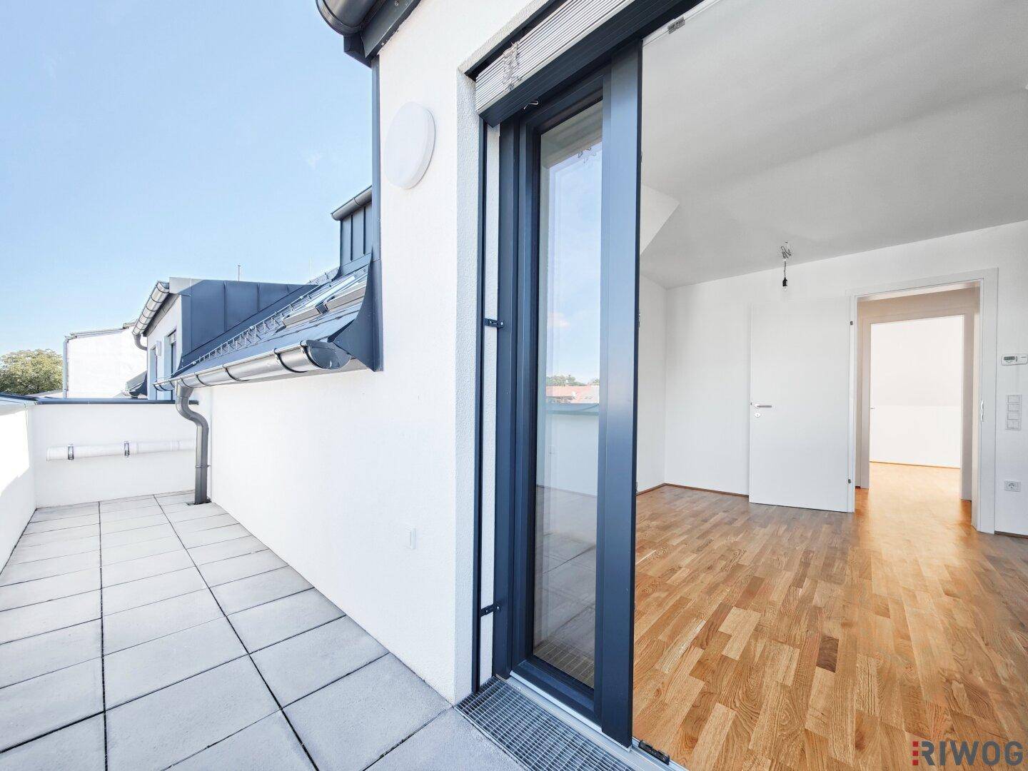 Sonniger Balkon mit Fliesenboden und Blick auf die umliegenden Dächer, zugänglich vom Innenbereich.