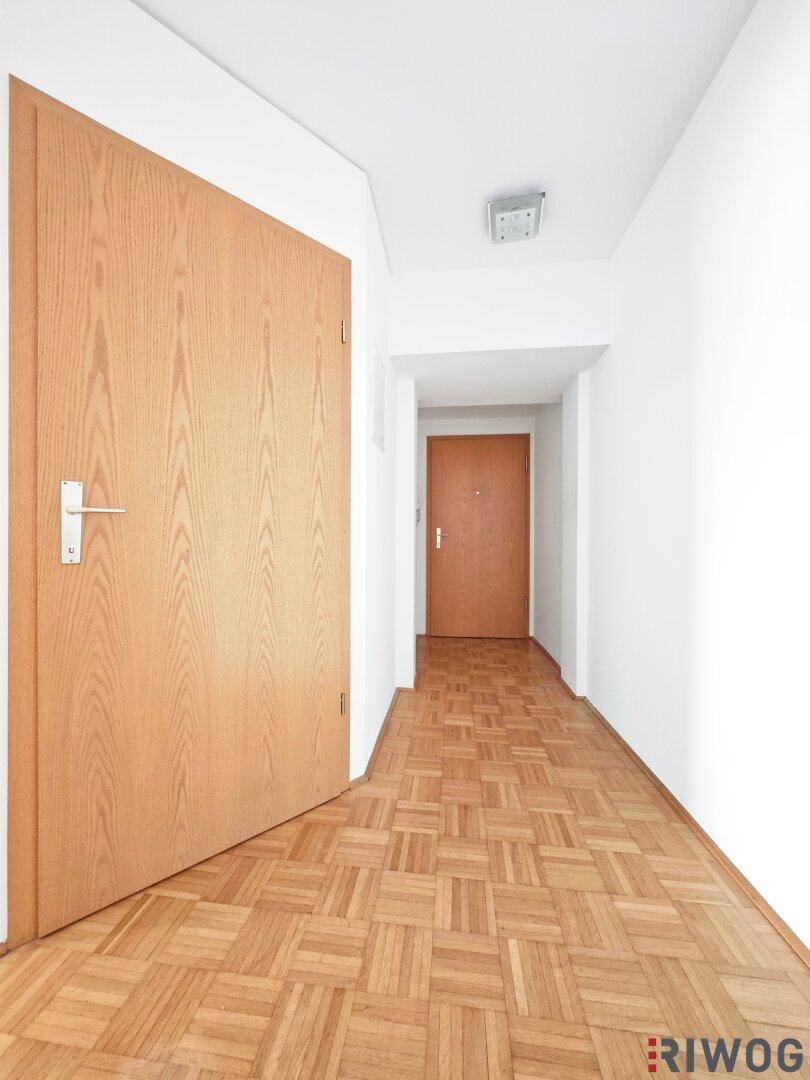 Heller Flur mit Parkettboden und Holztüren, der zu weiteren Räumen der Wohnung führt.