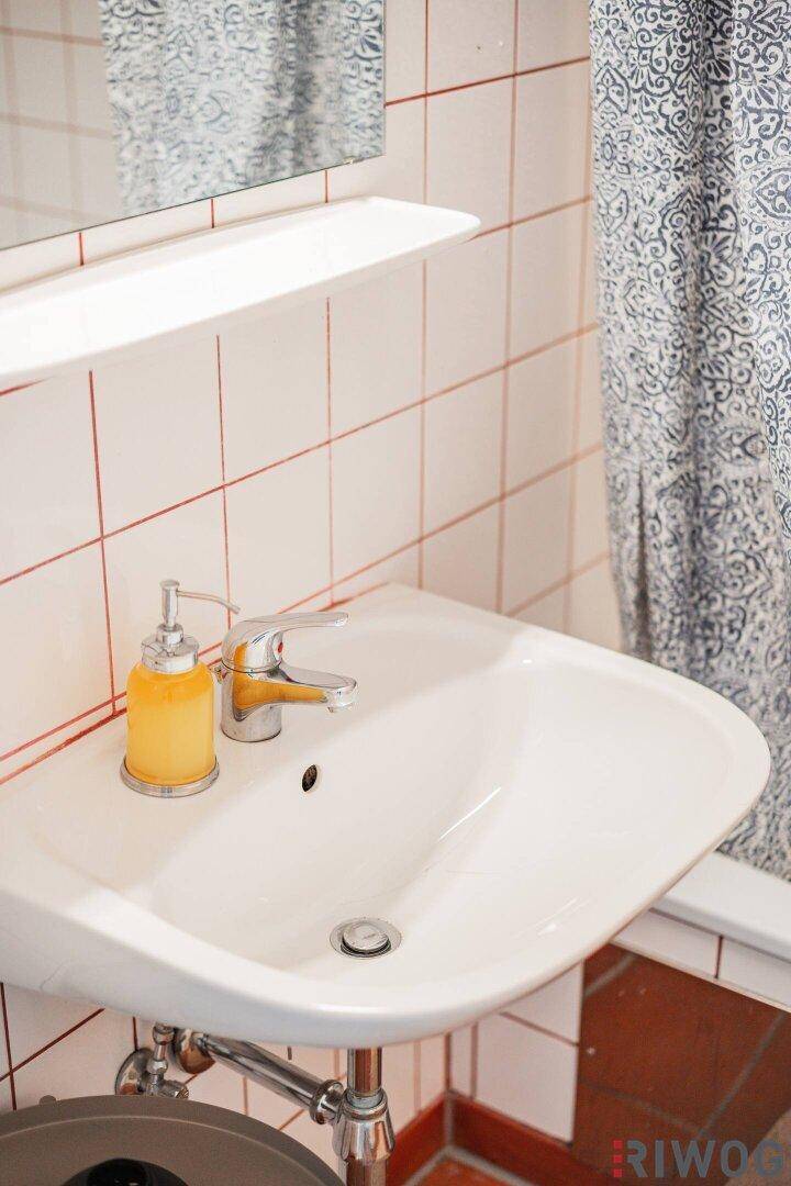 Nahaufnahme des Waschbeckens im Badezimmer mit Seifenspender und Spiegel.