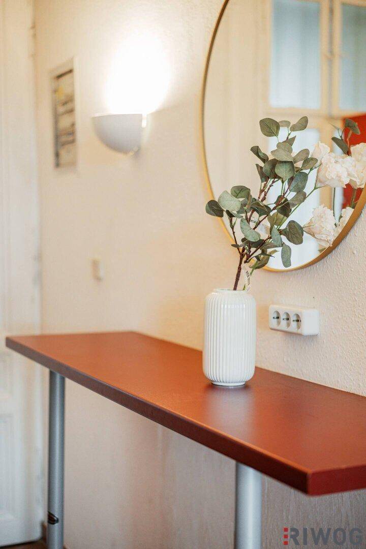 Detailansicht eines Konsolentisches mit Spiegel und Vase im Eingangsbereich oder Flur.