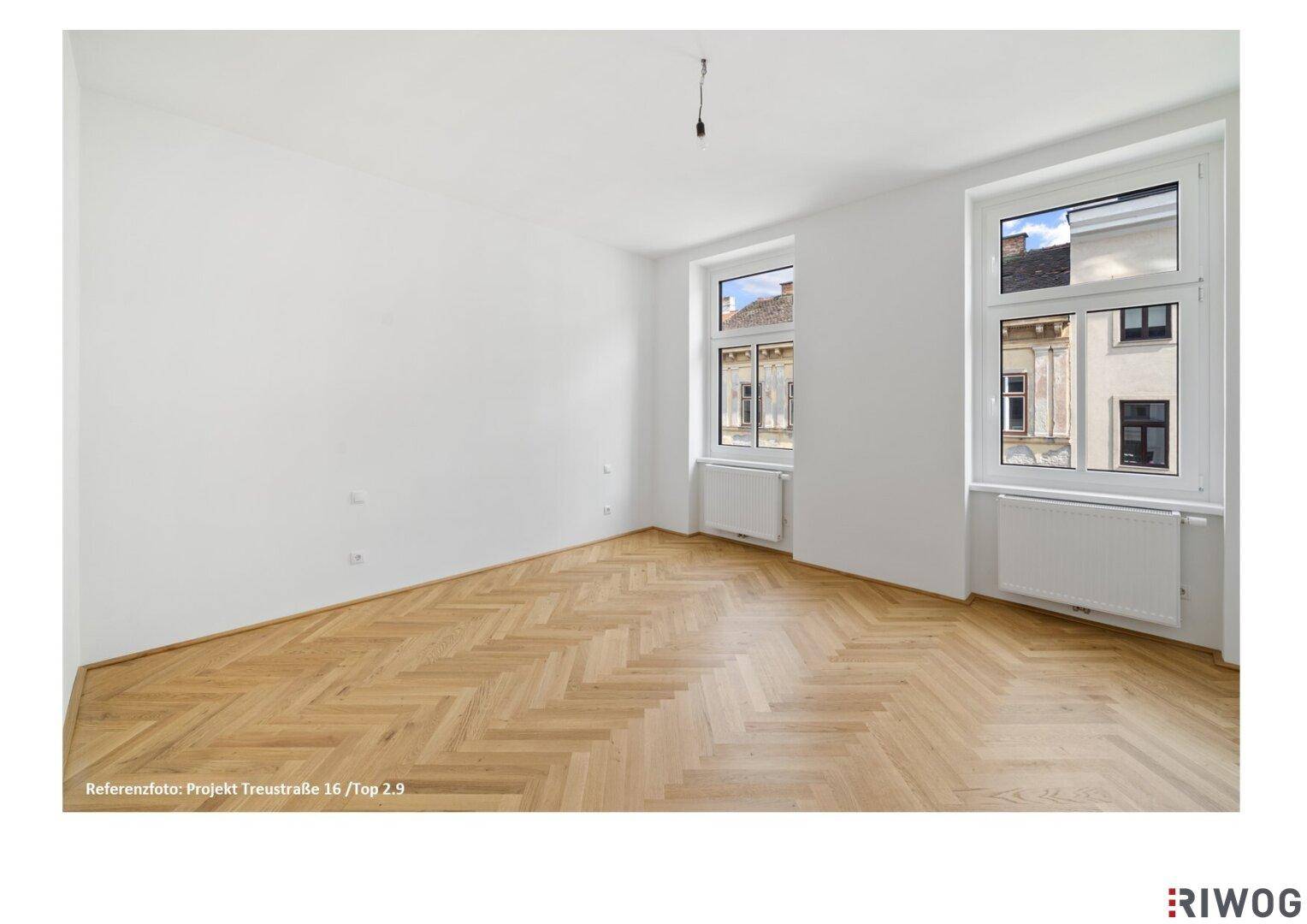 Helles Schlafzimmer mit Fischgrätparkett und zwei großen Fenstern zur Straße.
