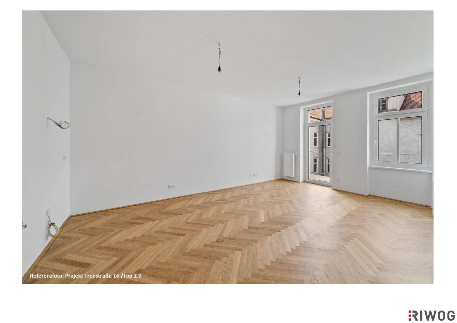 Heller, leerer Raum mit Fischgrätparkett und Zugang zu einem französischen Balkon.