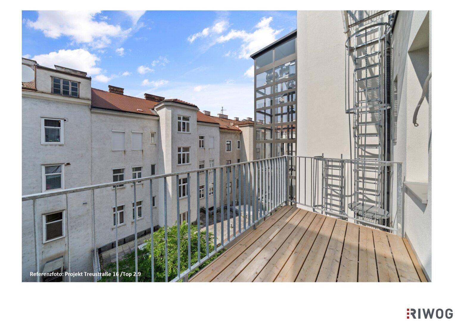Balkon mit Holzboden und Blick auf den Innenhof sowie einen modernen Glasaufzug des Gebäudes.