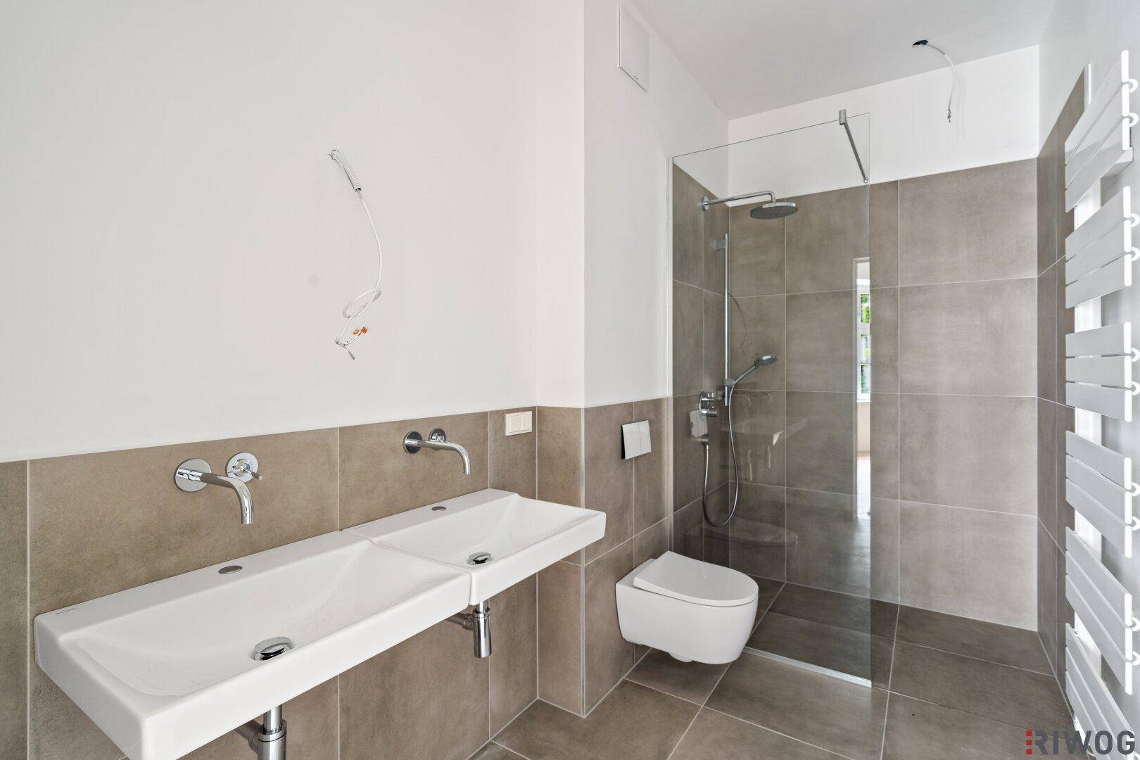 Modernes Badezimmer mit Doppelwaschbecken, ebenerdiger Dusche und beheiztem Handtuchhalter.