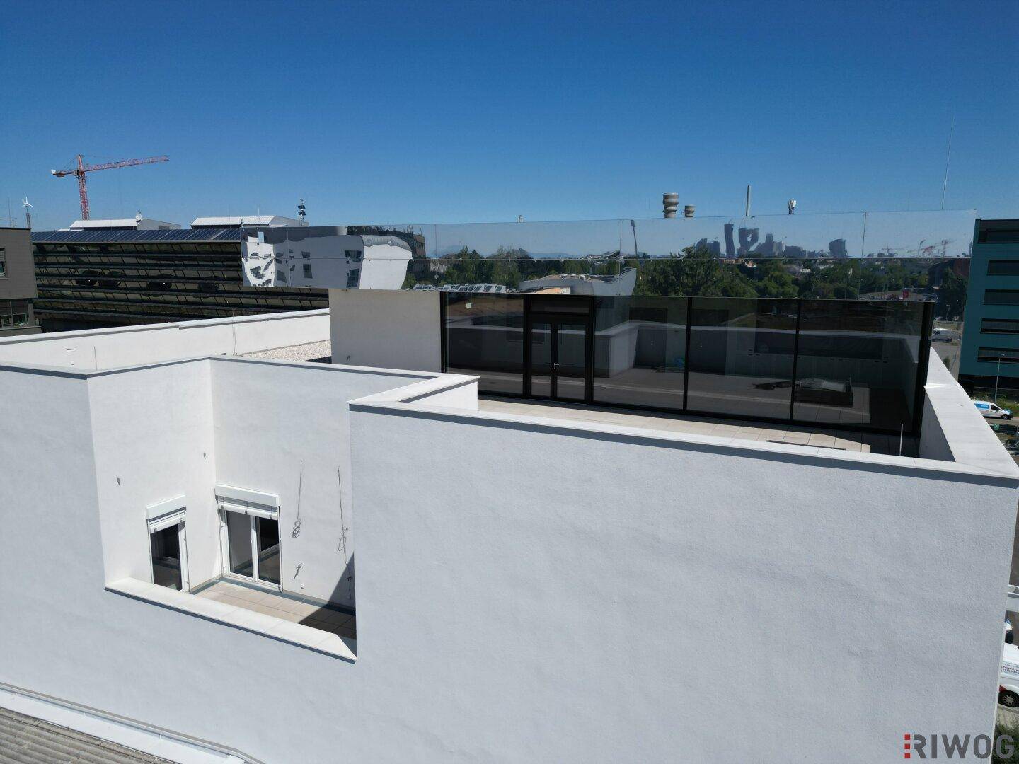Dachansicht mit einer modernen Glasfassade und einem kleinen, zurückgesetzten Fensterbereich mit Rollläden.