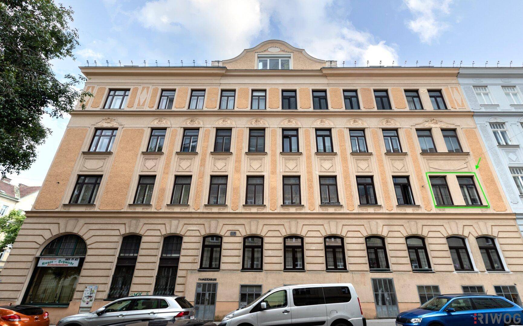Historische Gebäudefassade mit vielen Fenstern und einer hervorgehobenen Wohnung im zweiten Stock.