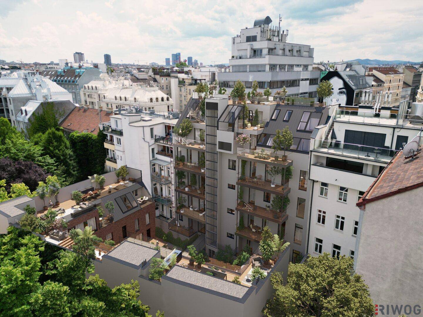 Vogelperspektive auf eine moderne Wohnanlage mit Terrassen und Balkonen, umgeben von grünen Bäumen und Stadtgebäuden.