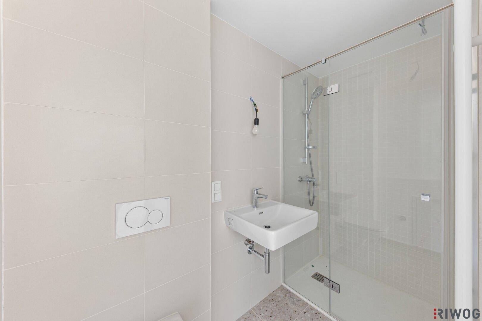 Modernes Badezimmer mit ebenerdiger Dusche, Wand-WC und hellen Fliesen.