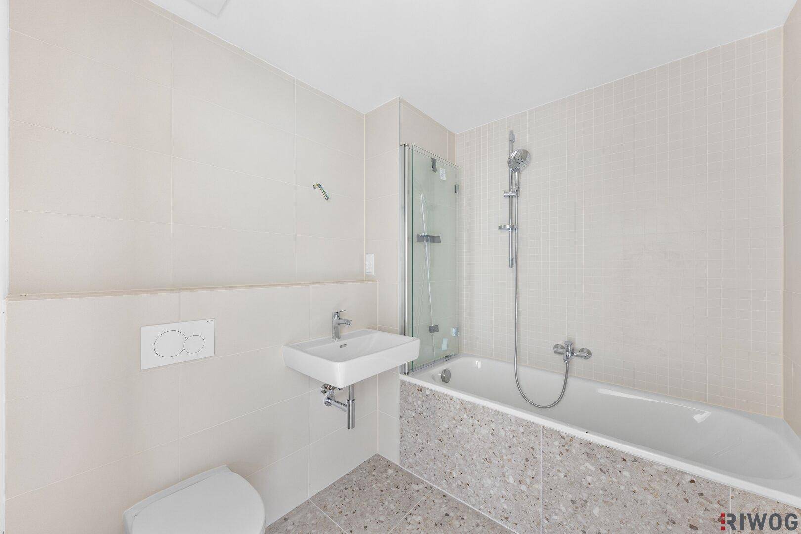 Modernes Badezimmer mit Badewanne, Waschbecken und WC, ausgestattet mit hellen Fliesen.