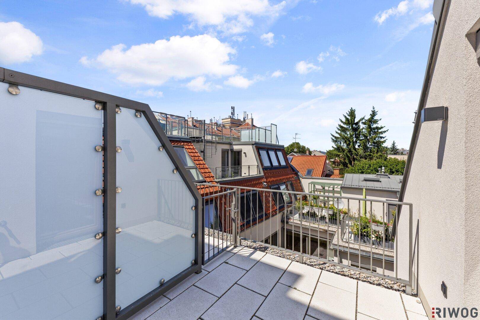 Sonniger Dachterrassenbereich mit Fliesenboden und Blick über die umliegenden Dächer.