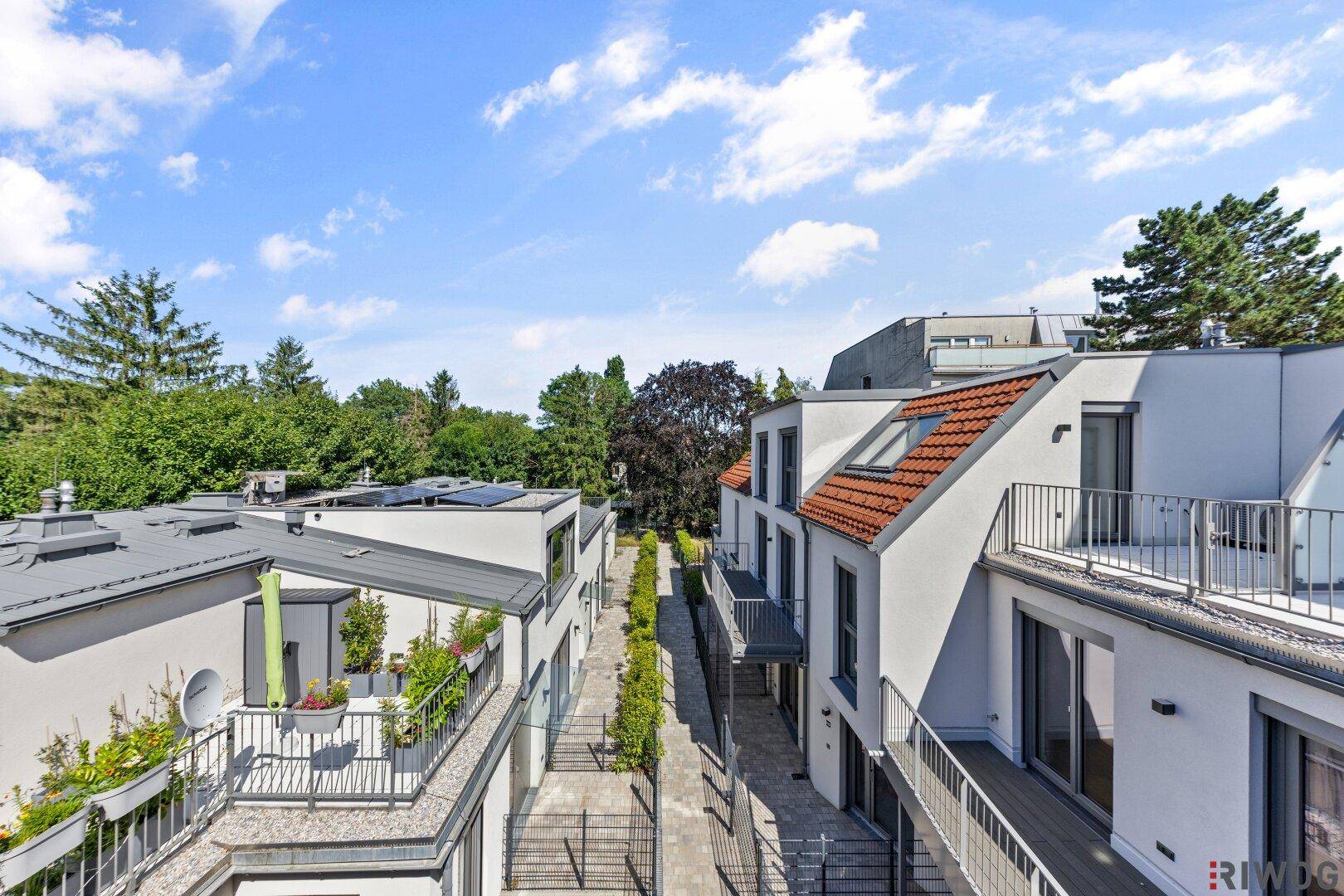 Luftaufnahme eines modernen Wohnkomplexes mit Reihenhäusern und viel Grün.
