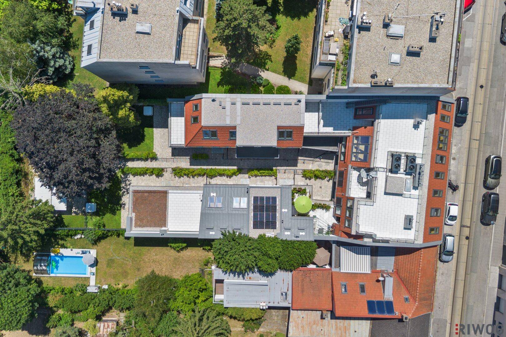 Vogelperspektive eines Wohnkomplexes mit Pool, Dachterrassen und viel Grün.