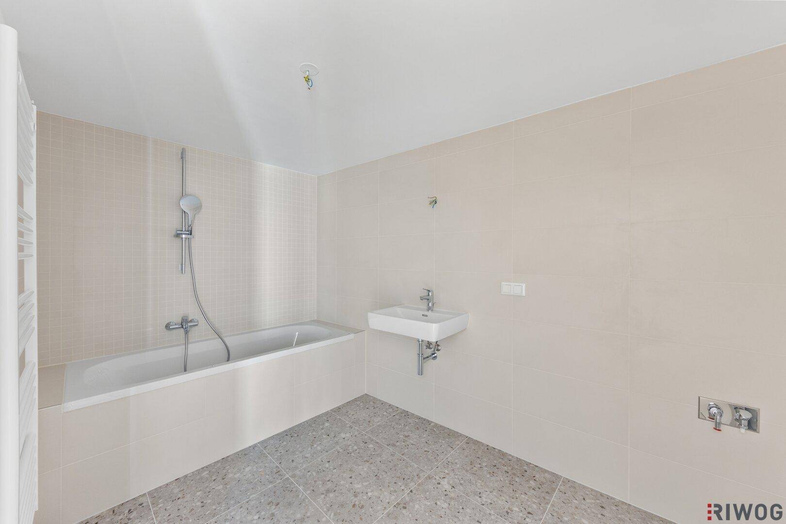 Modernes Badezimmer mit Badewanne, Waschbecken und hellen Fliesen.