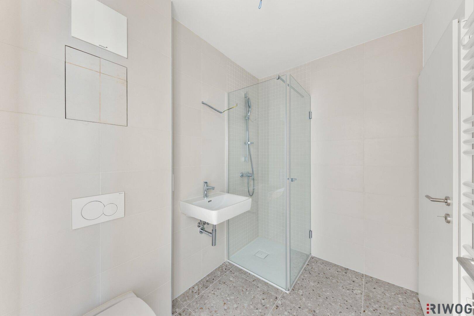 Helles Badezimmer mit Duschkabine, wandhängendem WC und modernem Waschbecken.