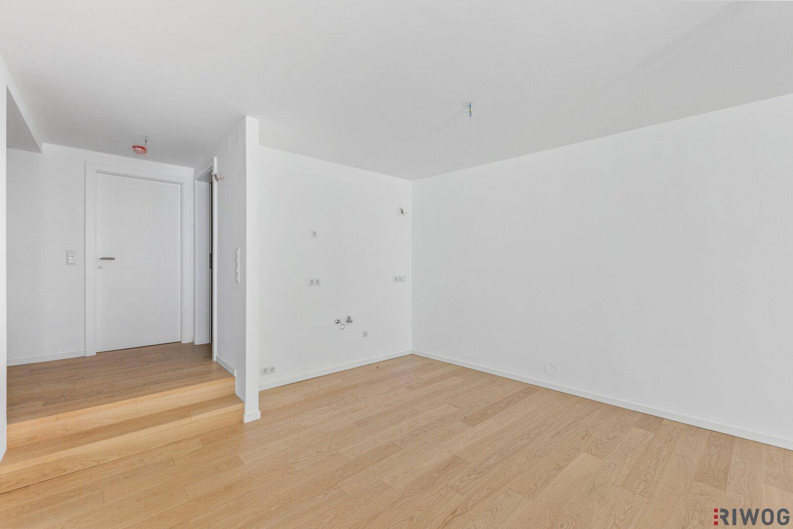 Heller Flurbereich mit Holzstufen und Zugang zu verschiedenen Zimmern im Neubau.