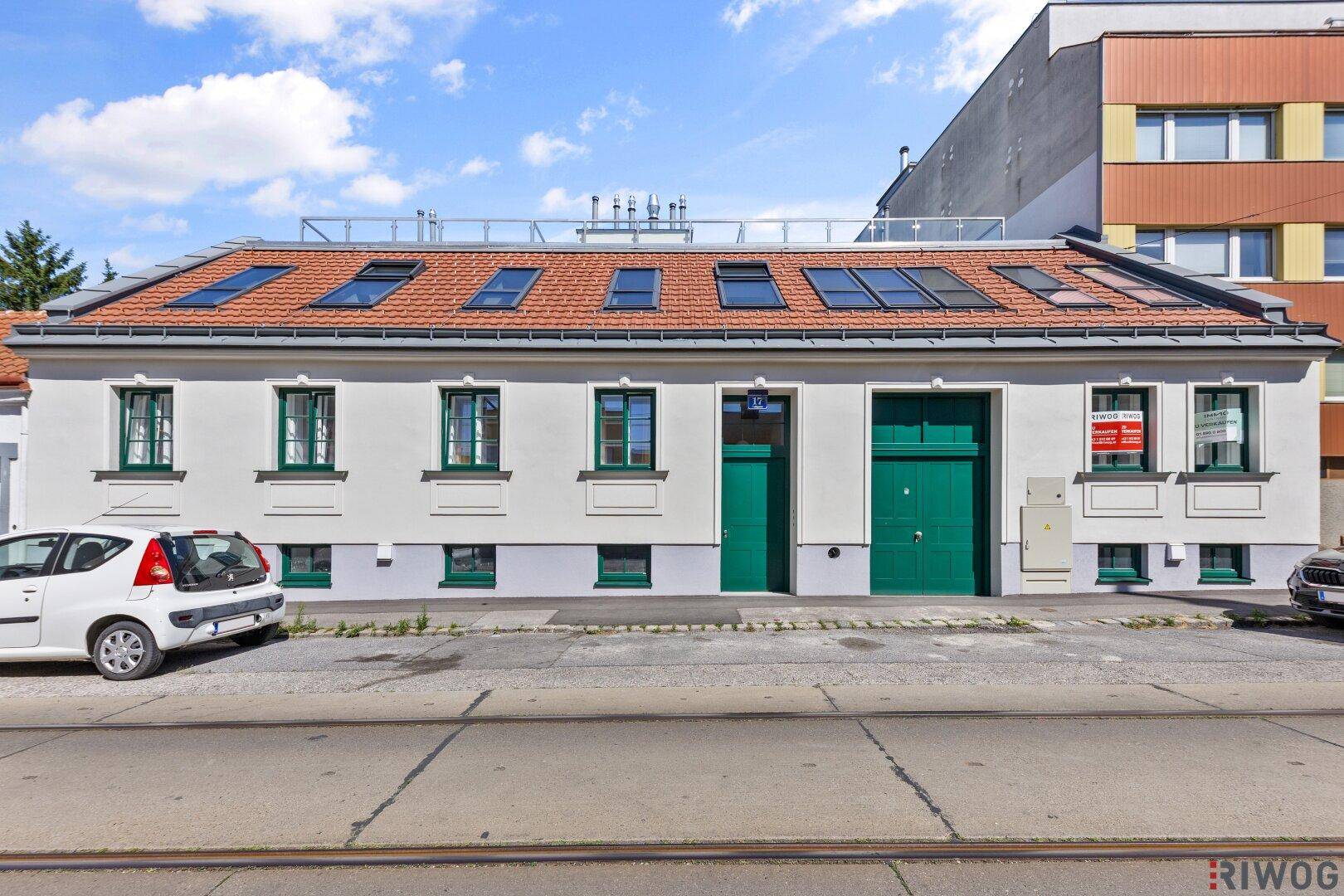 Fassade eines Gebäudes mit grünen Türen und Fenstern an einer städtischen Straße.