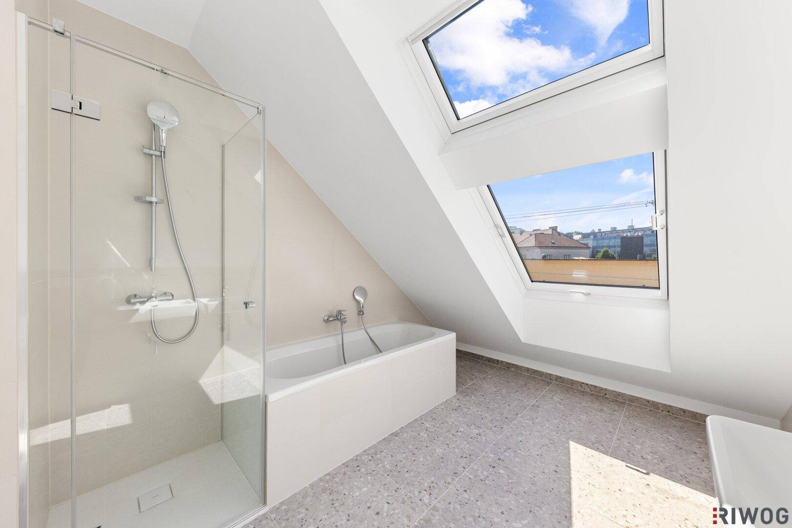 Modernes Badezimmer mit Badewanne, Dusche und Dachfenstern für viel Tageslicht.