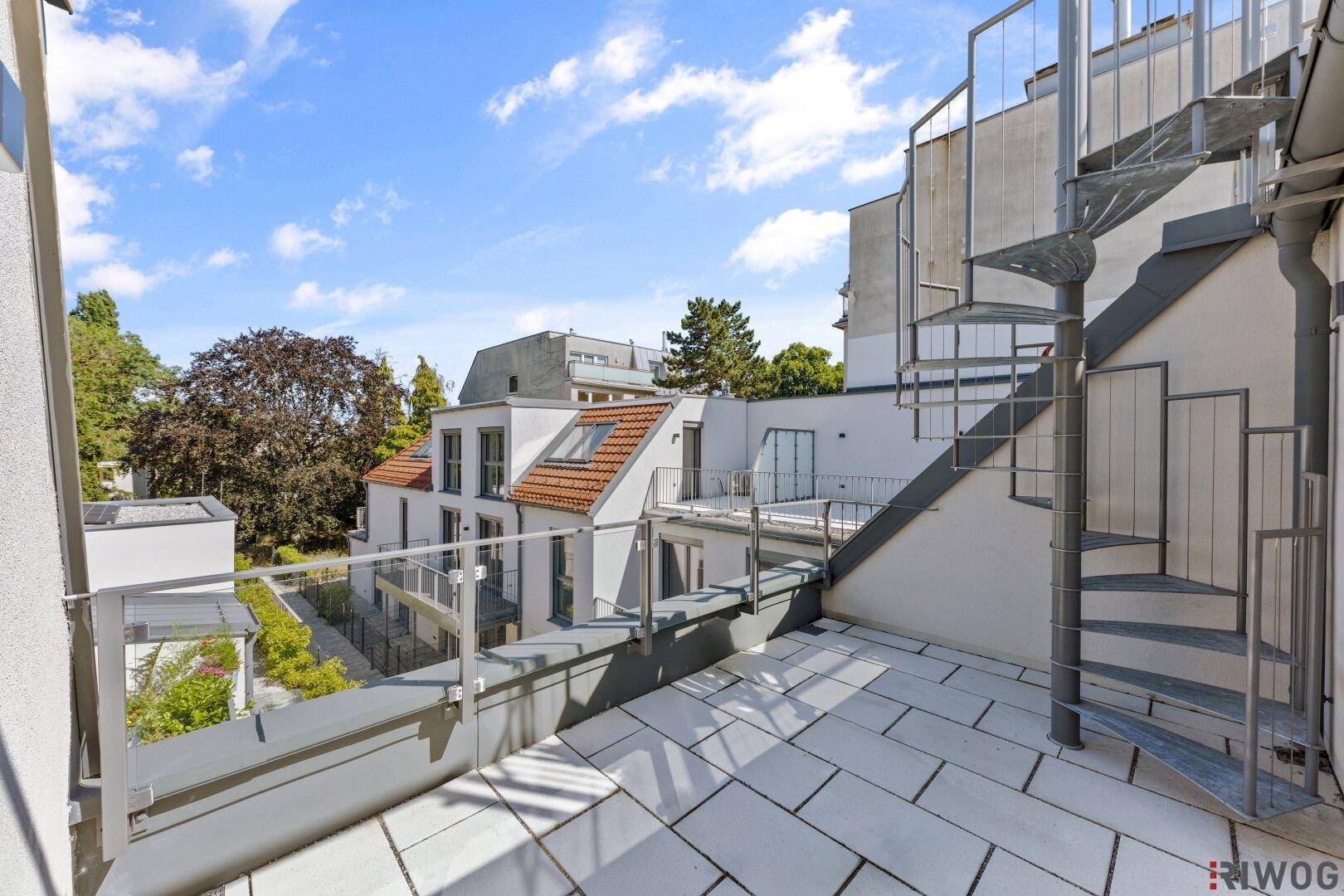 Große Dachterrasse mit Fliesenboden und einer Wendeltreppe zu weiteren Ebenen.