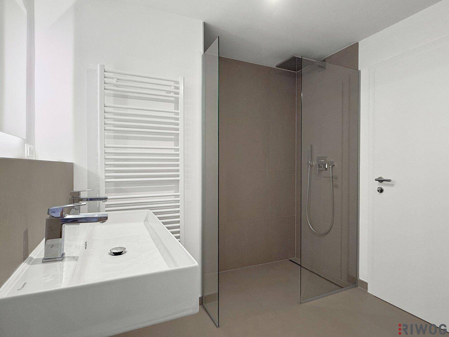 Modernes Badezimmer mit ebenerdiger Dusche, elegantem Waschbecken und beheiztem Handtuchhalter.