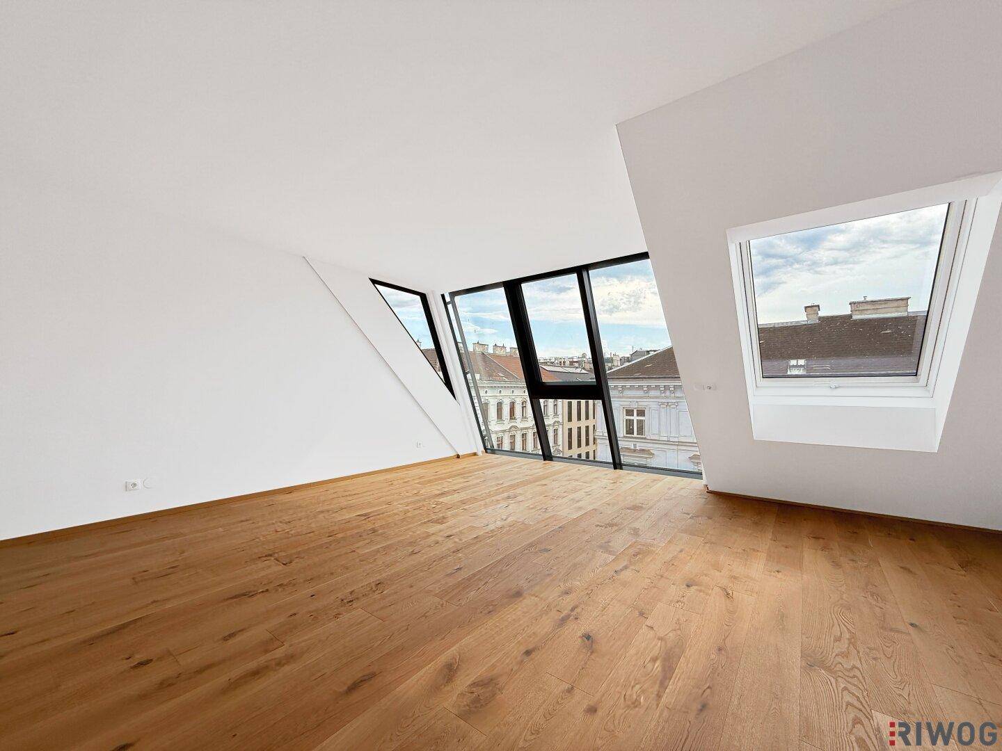 Heller Wohnraum mit Holzboden, großen Fenstern und Dachfenster, bietet eine moderne Wohnatmosphäre.