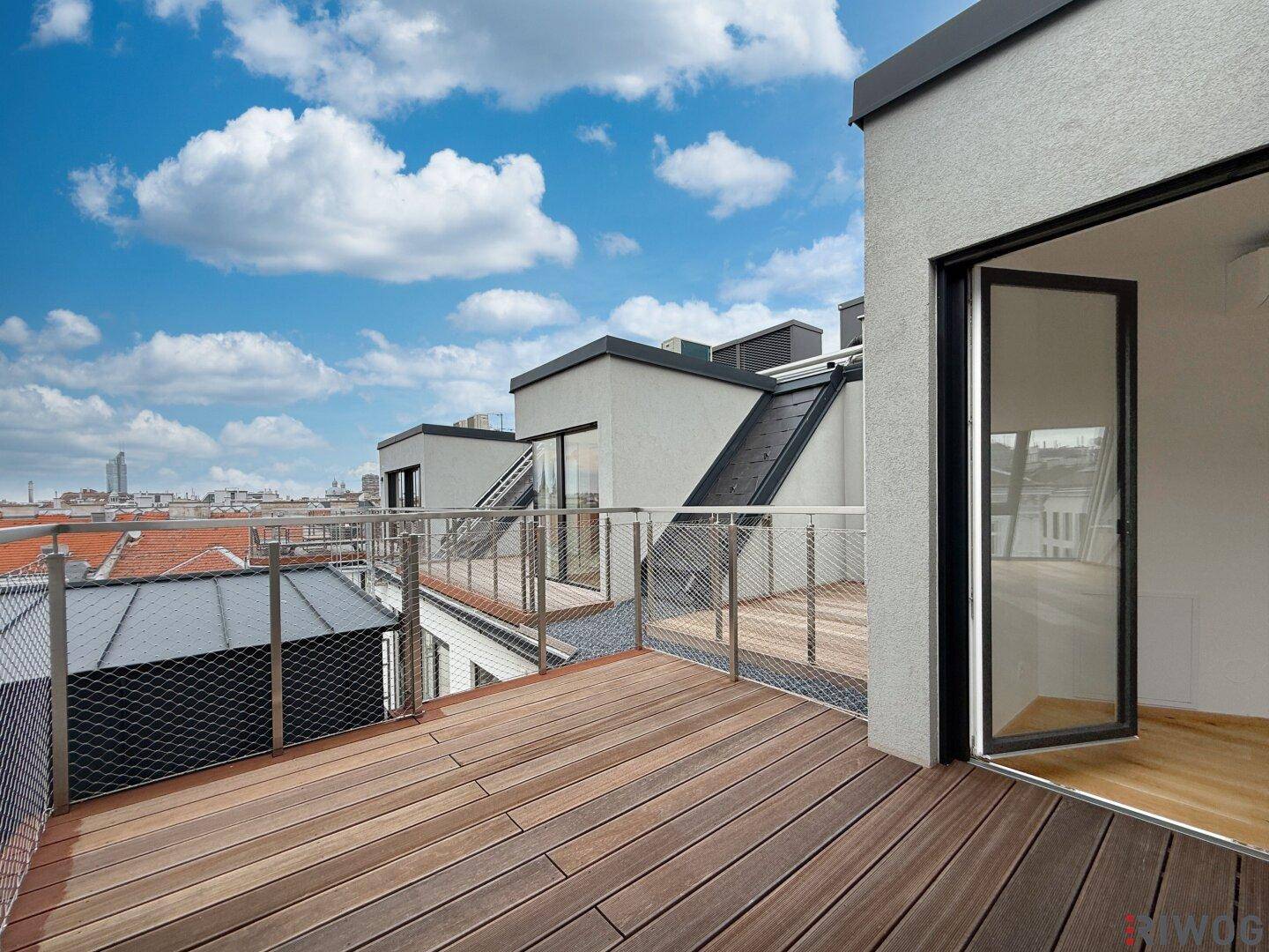 Weitläufige Dachterrasse mit Holzboden und Panoramablick über die Dächer und die Stadt.