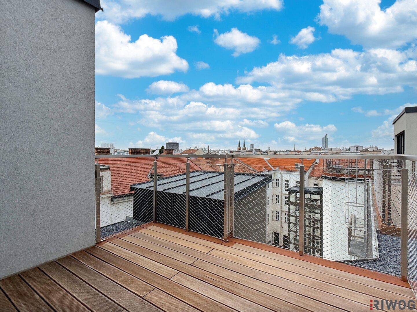 Geräumige Dachterrasse mit Holzboden und weitem Blick über die Dächer der Stadt.