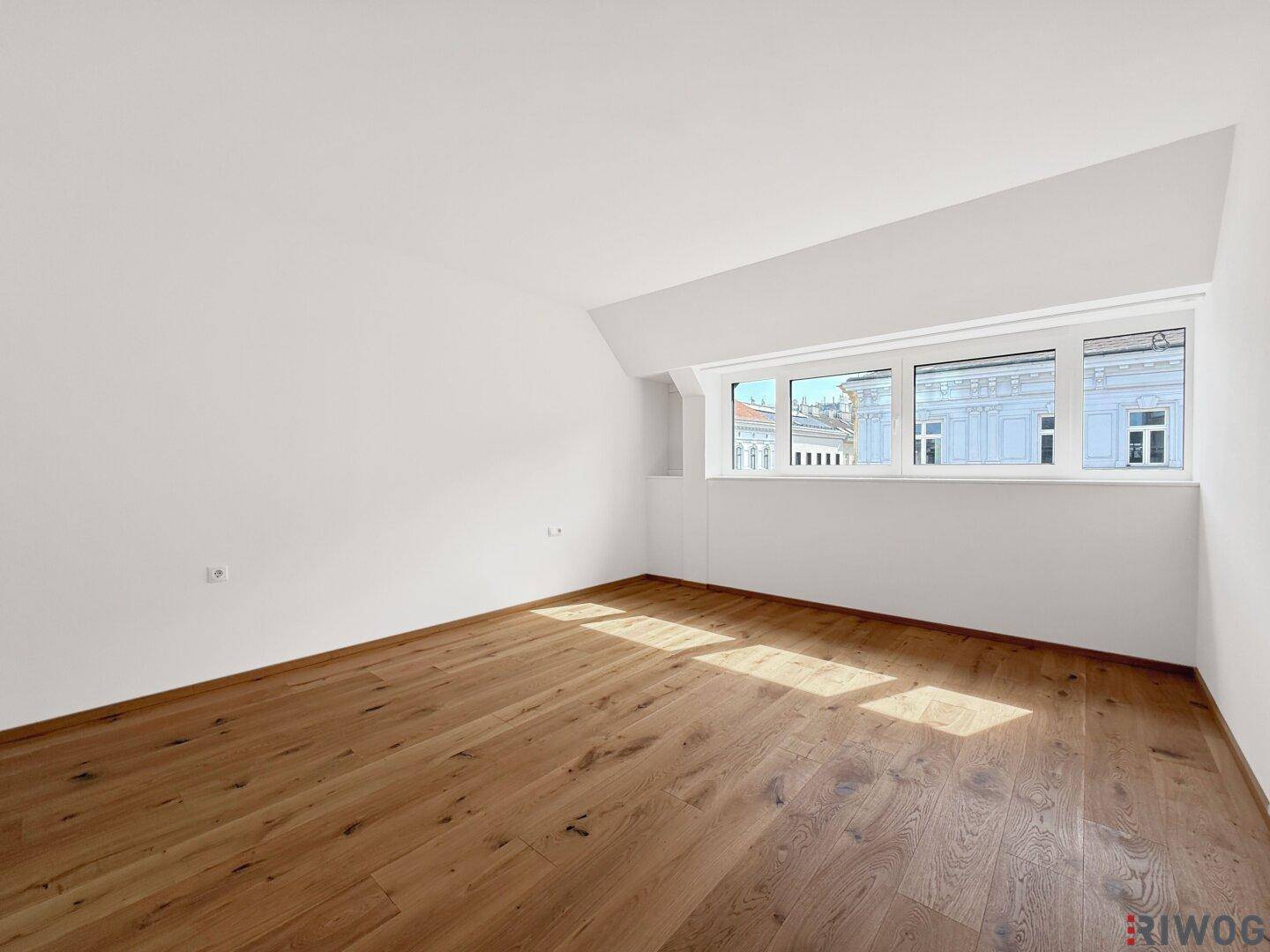 Helles Schlafzimmer mit Holzboden und breitem Fenster, bietet einen ruhigen Blick auf die Umgebung.