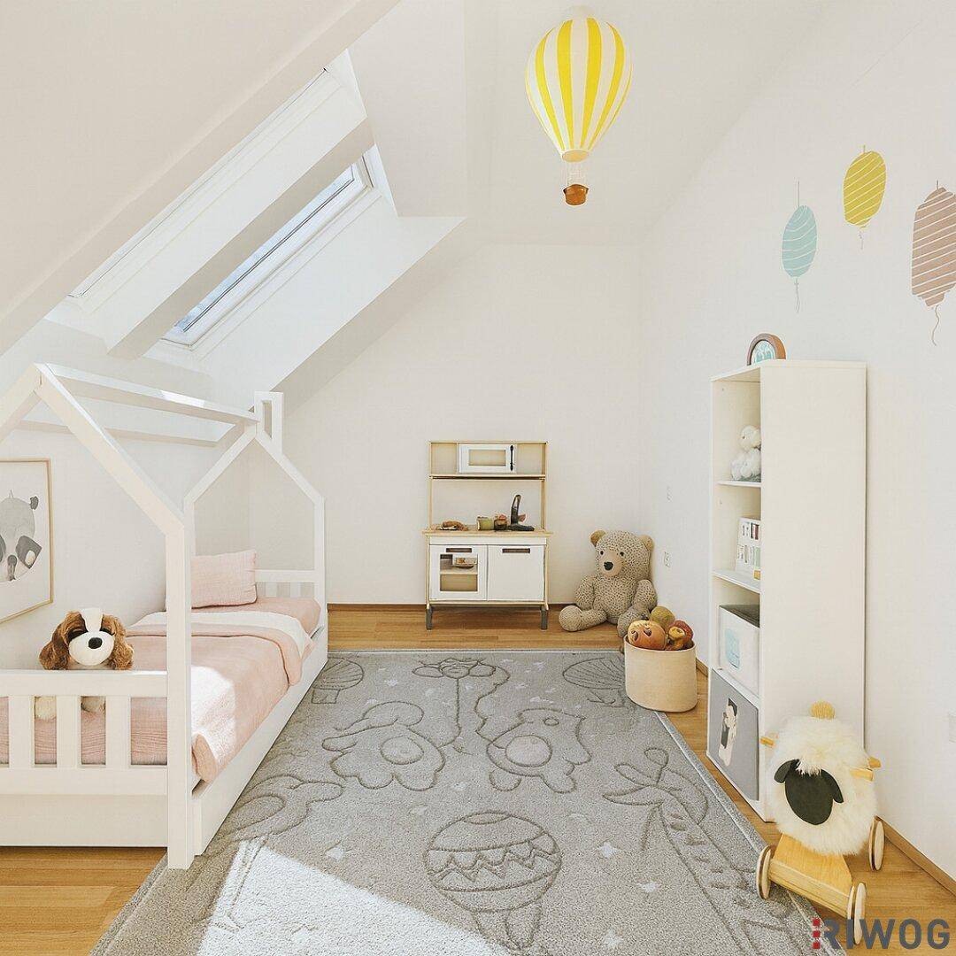 Freundliches Kinderzimmer im Dachgeschoss mit Spielbereich, Dachfenstern und Holzboden.