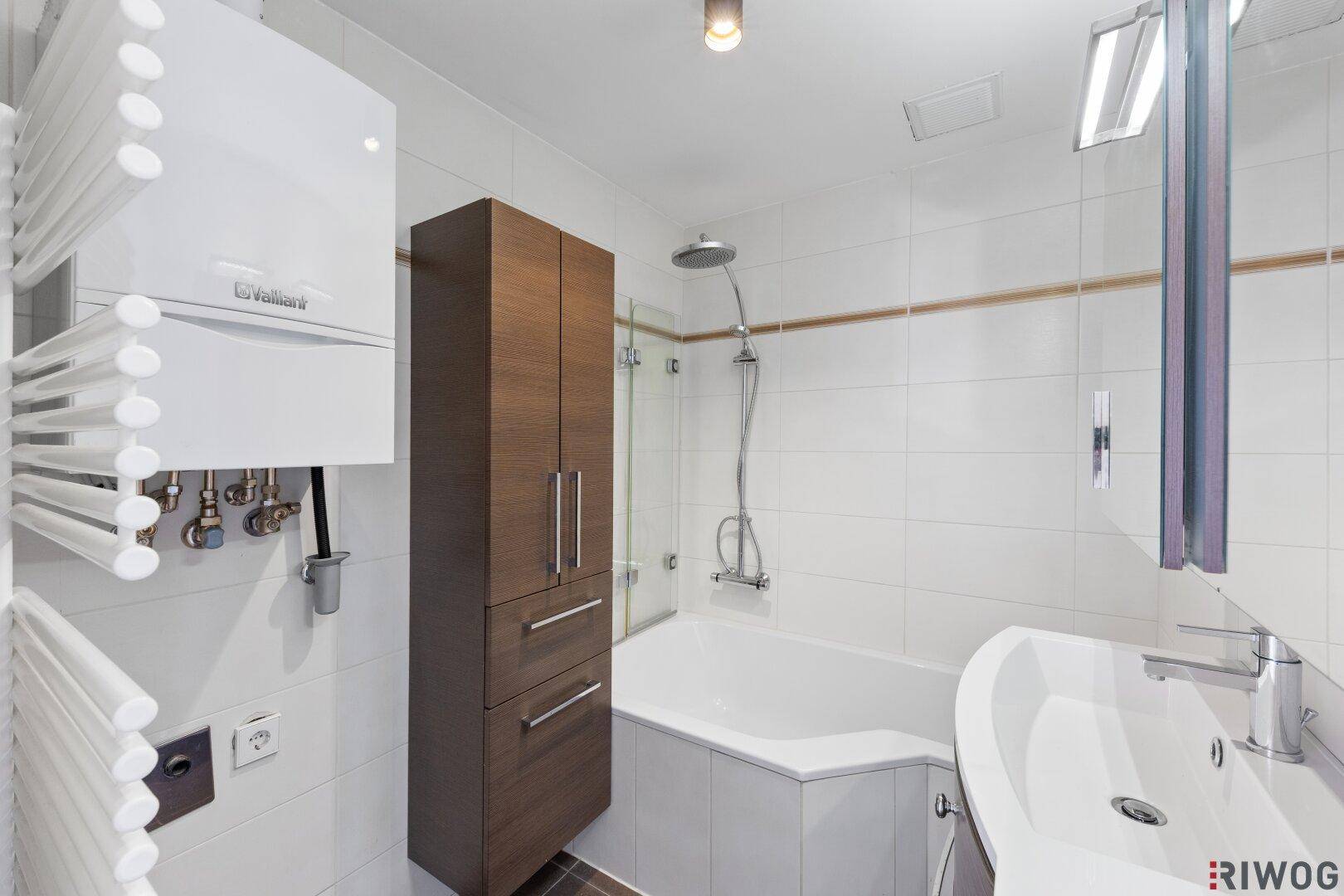 Modernes Badezimmer mit Badewanne, Dusche, Waschbecken und Handtuchheizkörper.
