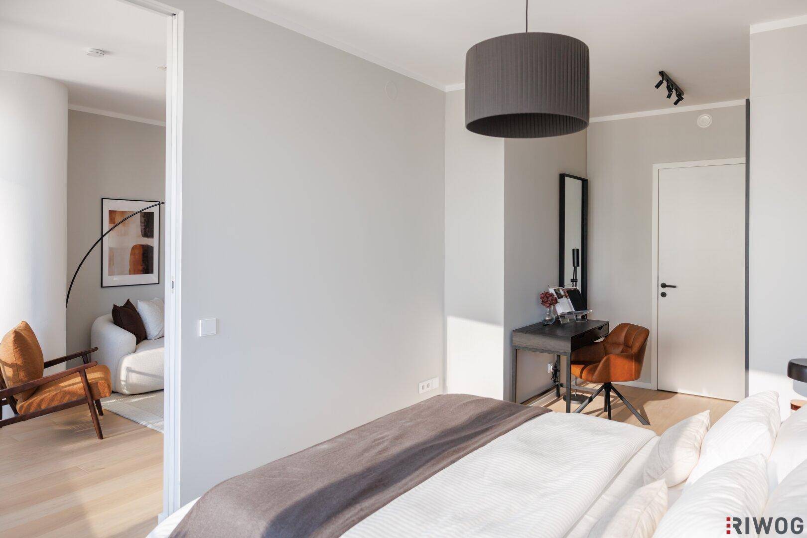 Helles Schlafzimmer mit großem Bett und Blick auf den angrenzenden Wohnbereich.