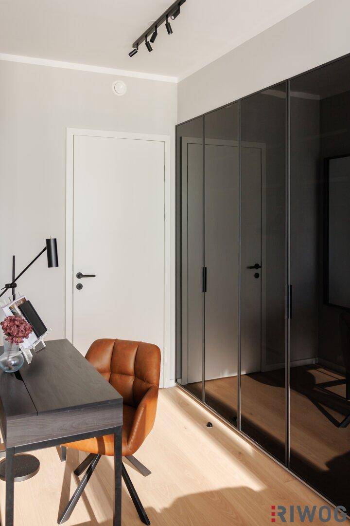 Arbeitsbereich mit Schreibtisch, Ledersessel und eleganten Spiegelschränken.