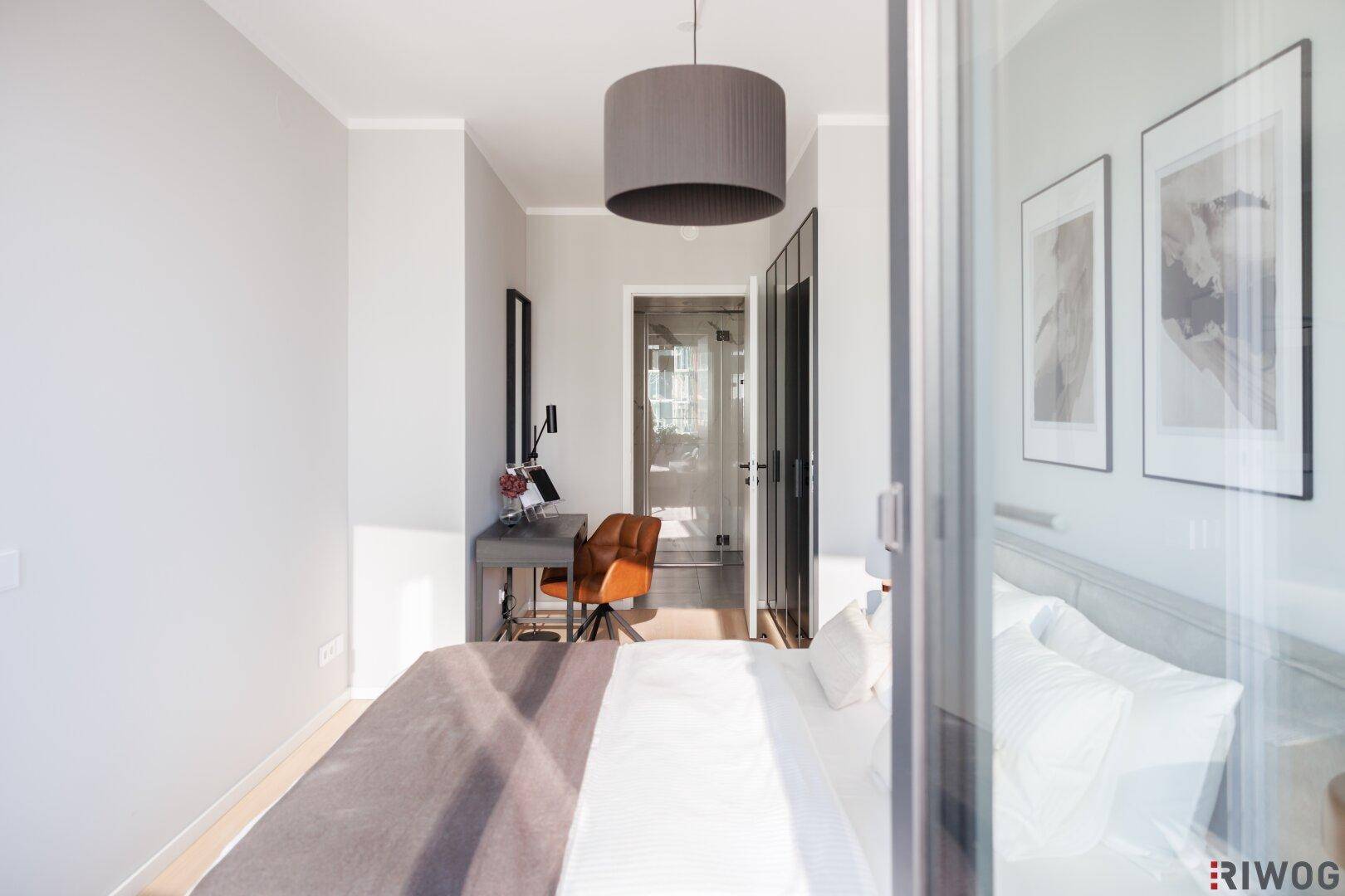 Schlafzimmer mit großem Bett, Spiegelschränken und Zugang zu einem hellen Bereich.