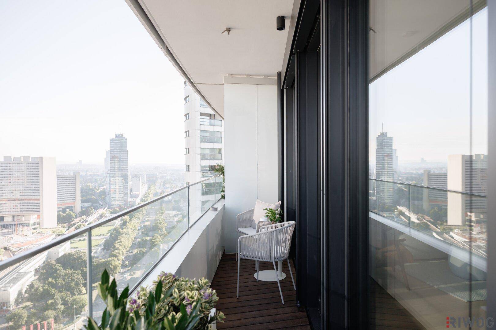 Heller Balkon mit Sitzgelegenheiten und beeindruckendem Blick auf die Stadtlandschaft.