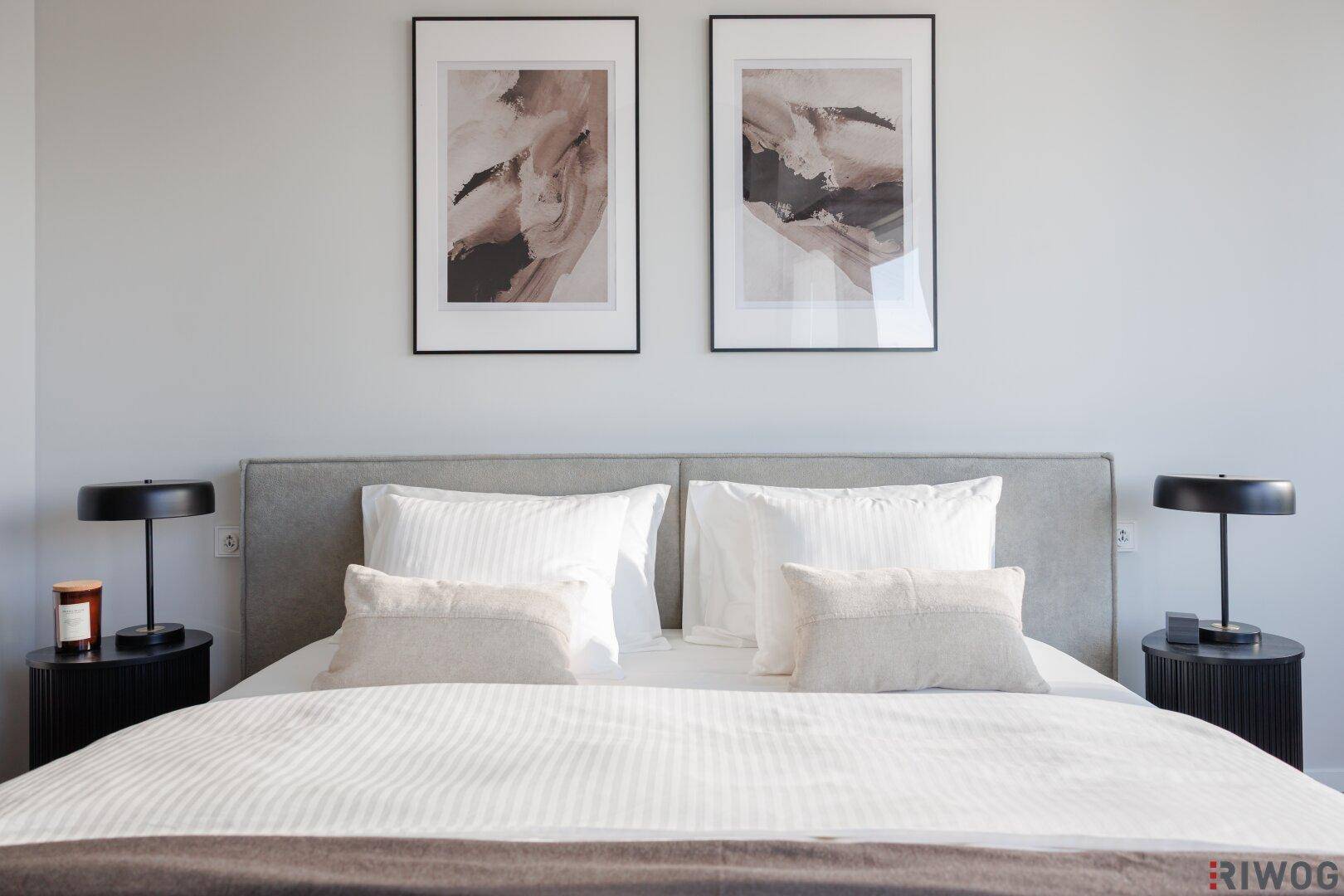Modernes Schlafzimmer mit großem Bett, Nachttischen und abstrakten Kunstwerken an der Wand.