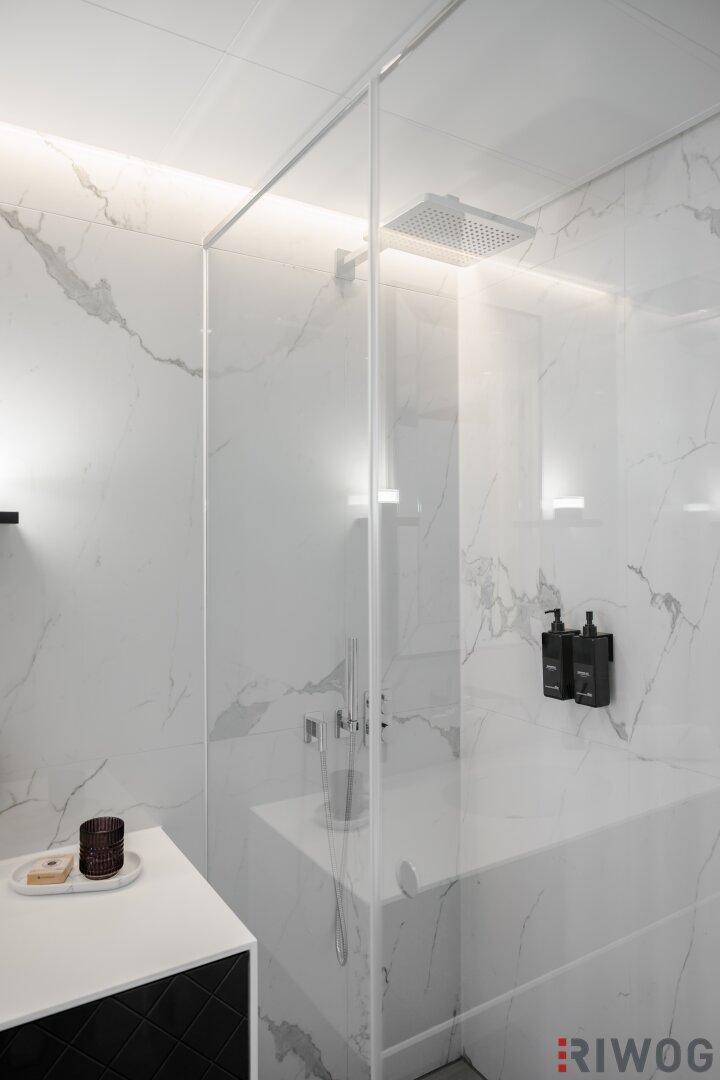 Moderne Dusche mit Regenduschkopf und eleganten Marmorfliesen an den Wänden.