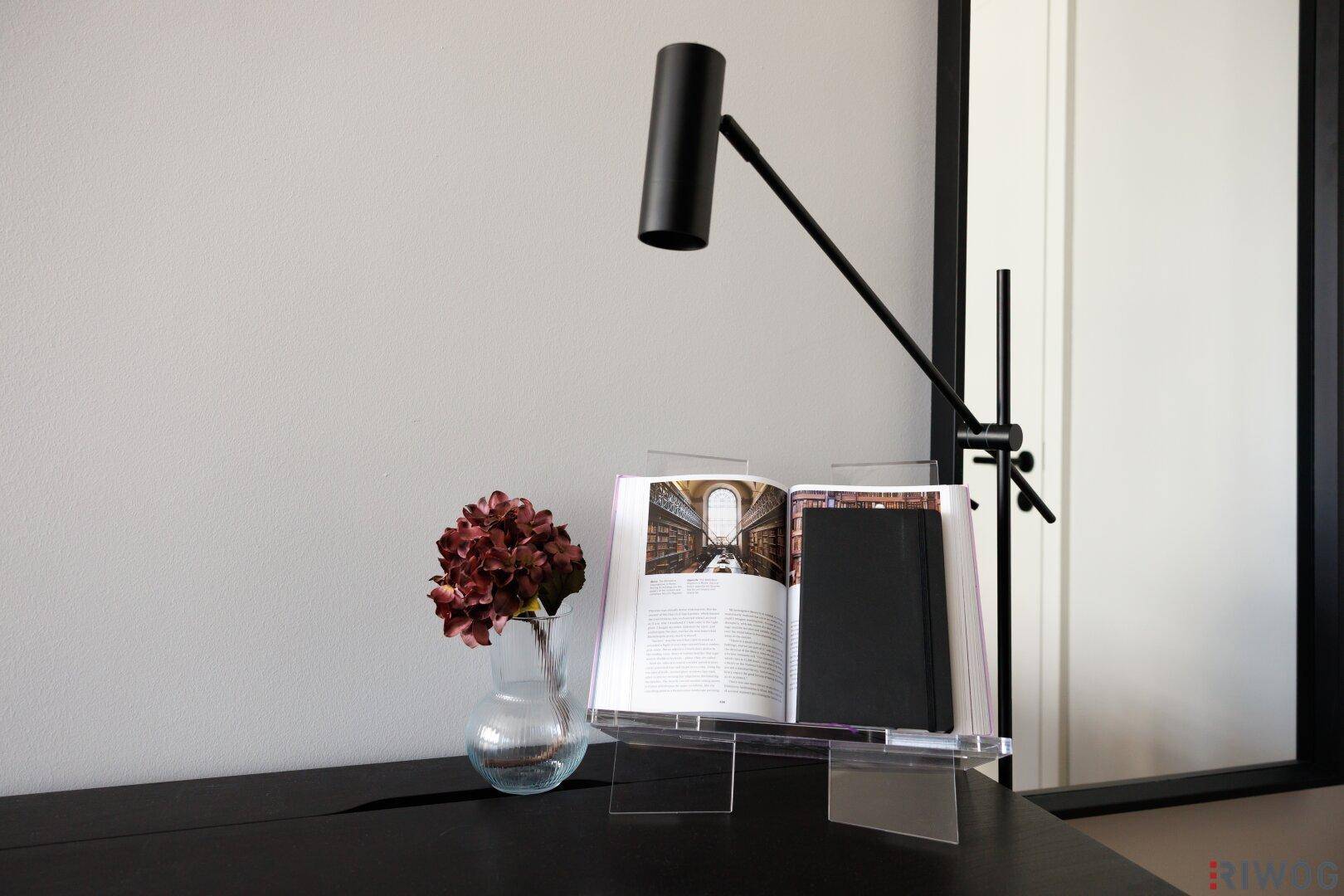 Nahaufnahme von Schreibtischaccessoires, darunter eine Lampe, ein Buch und eine Vase.