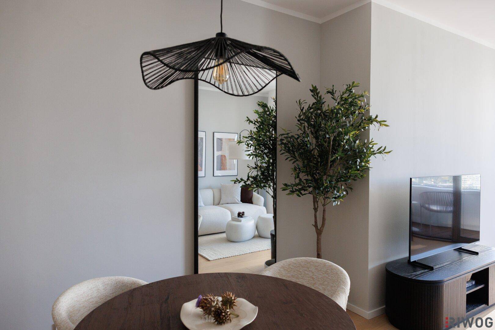 Essbereich mit modernem Esstisch, Designerlampe und großem Wandspiegel.