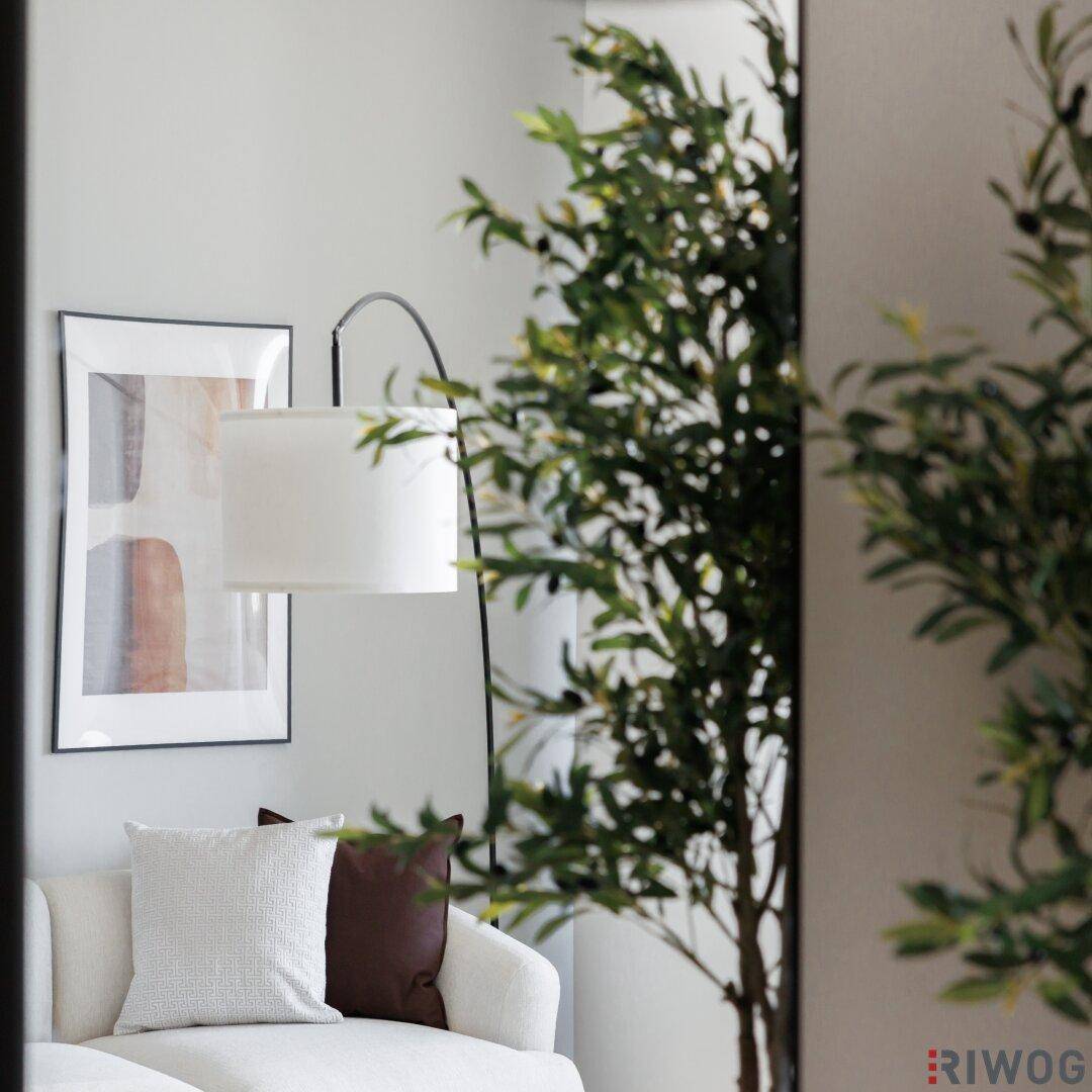 Detailansicht des Wohnbereichs mit Sofa, Stehlampe und abstrakten Bildern.