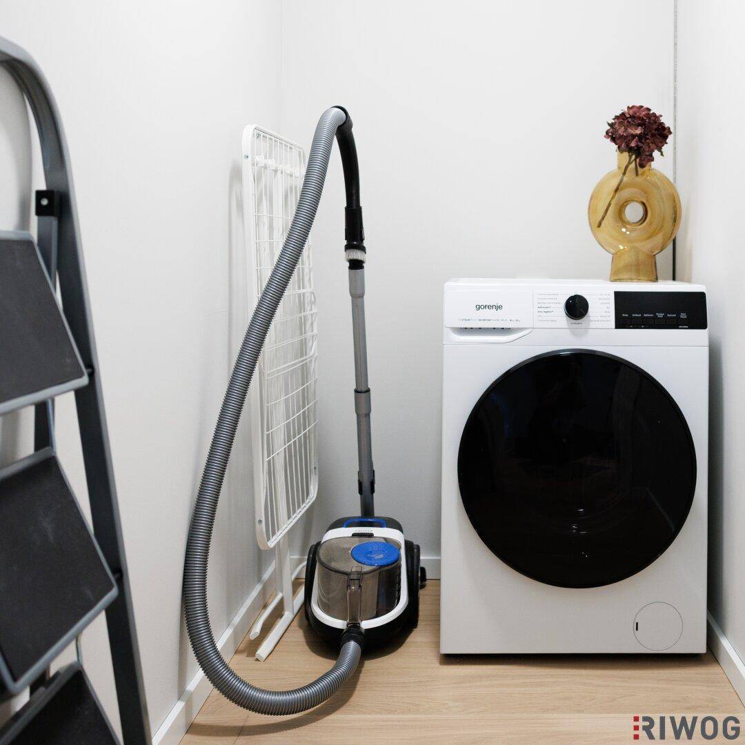 Praktischer Hauswirtschaftsraum mit Waschmaschine, Staubsauger und Wäscheständer für den Alltag.