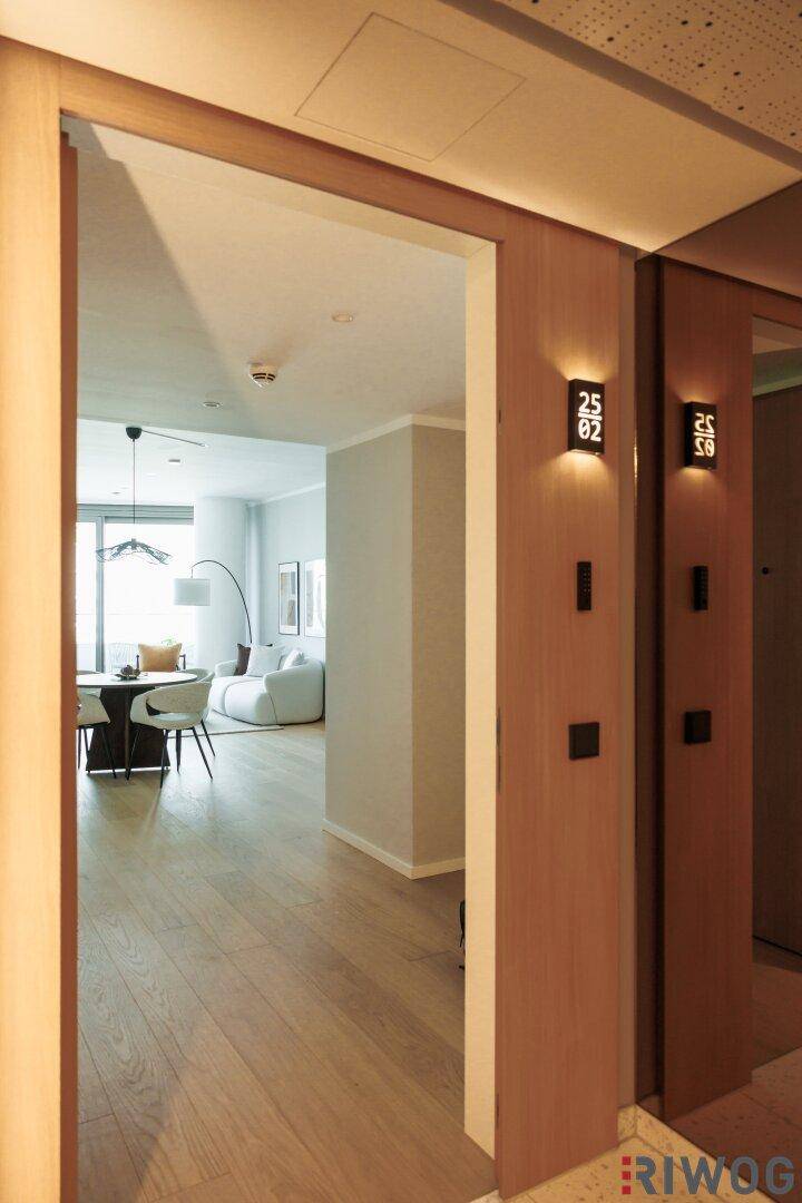 Heller Eingangsbereich mit Holzboden, der in den offenen Wohnbereich der Wohnung führt.