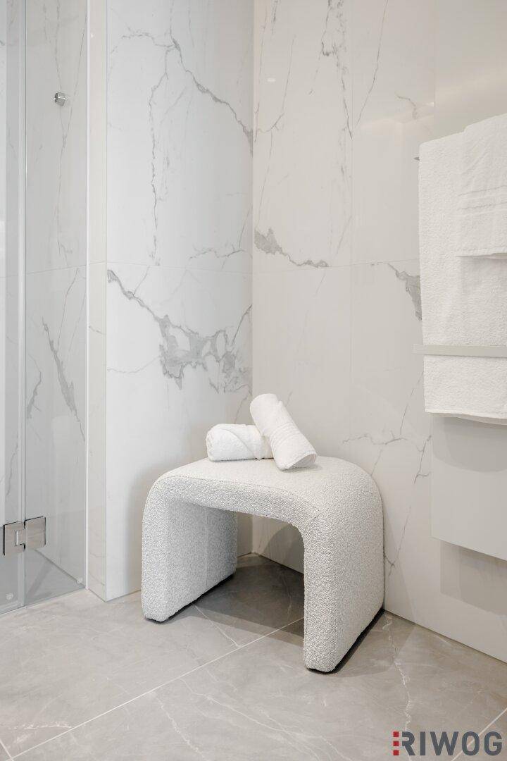 Modernes Badezimmer mit grauen Bodenfliesen und einer stilvollen Sitzgelegenheit.