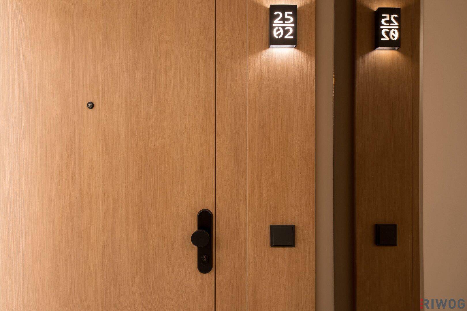 Eingangstür aus Holz mit moderner Beleuchtung und stilvollen Details, die den Flur aufwerten.