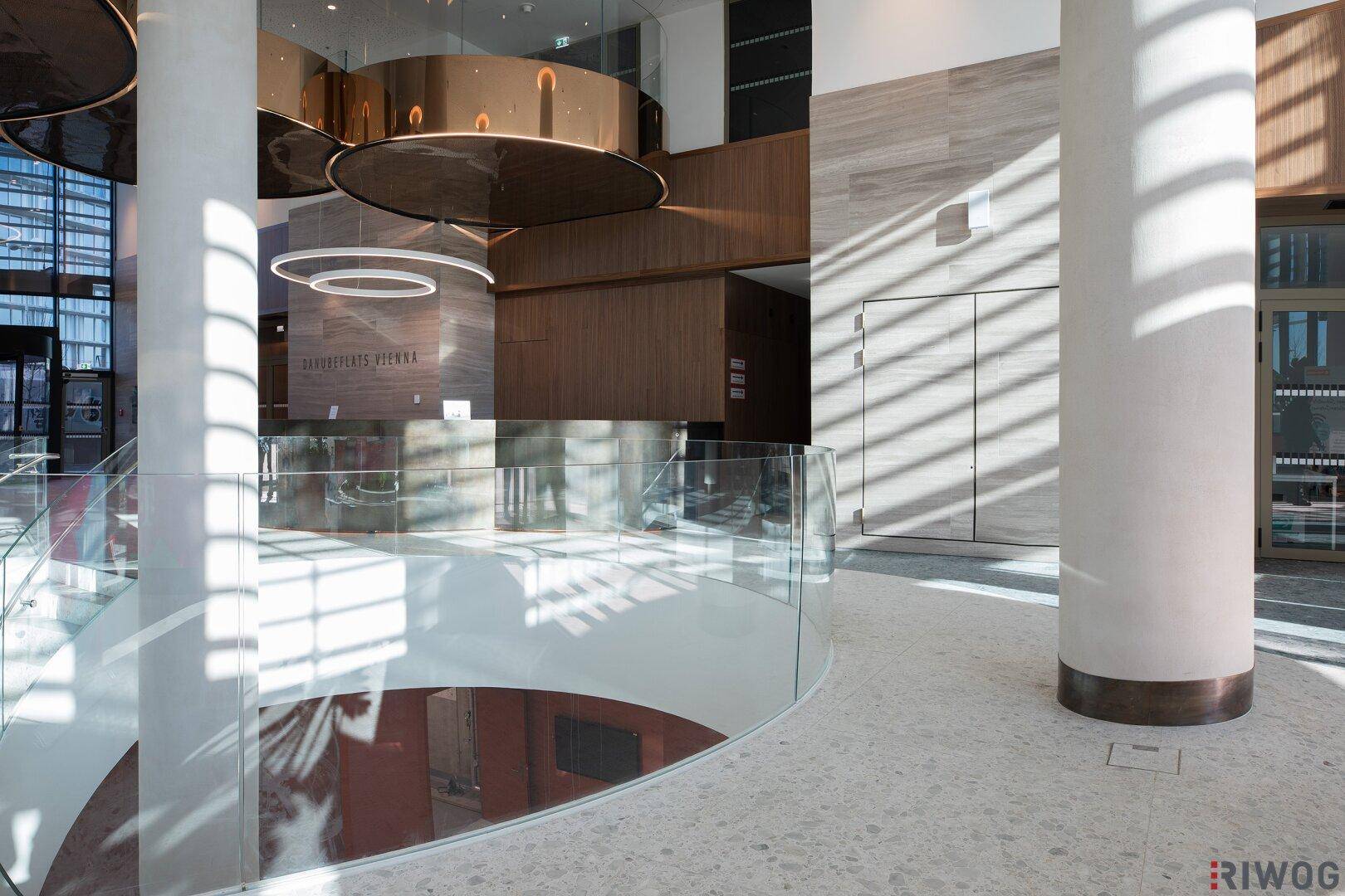 Blick von der oberen Etage der Lobby auf den unteren Bereich mit Säulen und moderner Gestaltung.